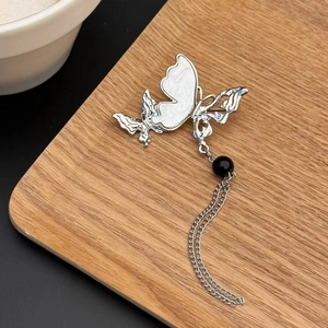 Broche papillon argentée avec incrustation en nacre, perle noire et pampilles