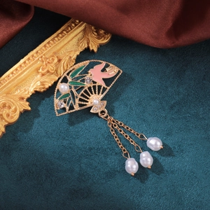 Detailed shot of a vintage gold fan brooch with enamel birds and pearl tassel charms