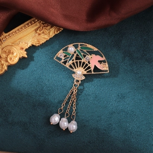 Close-up of fan brooch with green bamboo leaves, pink bird, and pearl tassels