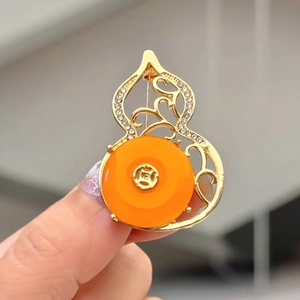 Detailed view of a gold hollow gourd brooch featuring an orange stone and crystal accents