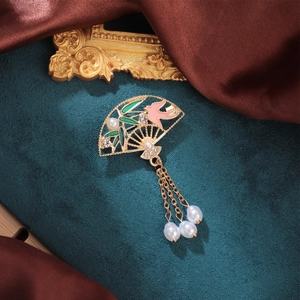 Detail of a vintage Chinese fan brooch with gold hollow frame, green bamboo and pearls