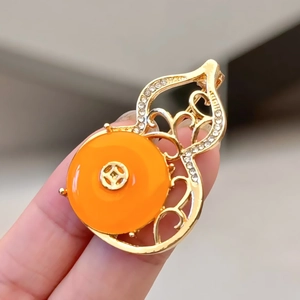 Detailed view of a gold gourd brooch featuring orange stone and sparkling crystals