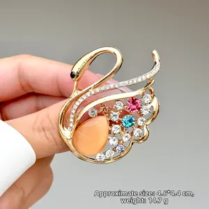 Detalle de broche de cisne con cristales coloridos y pedrería sostenido por una mano