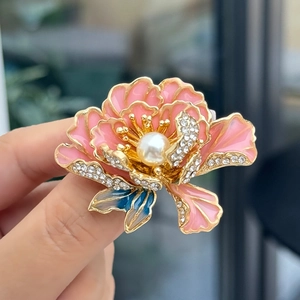Macro detail van een pioenroos broche met roze emaille bloemblaadjes en parel