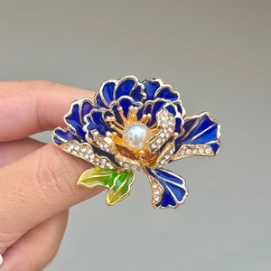 Detail van blauwe emaille pioenroos broche met witte parel en gouden randen