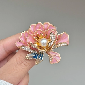 Macro-opname van de pioenroos broche met roze emaille blaadjes en parel in het midden