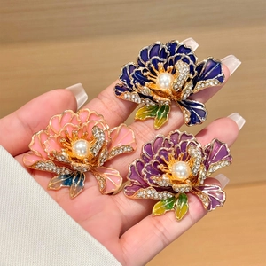 Detailopname van pioenroosbroches met goudkleurige basis en kleurrijke emaille bloemen