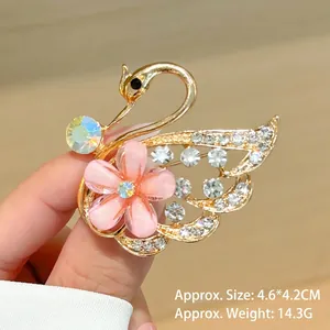 Detalle del broche de cisne con diamantes y flor rosa mostrando tamaño 4,6x4,2cm en madera