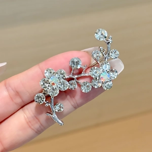 Detailed close-up of a silver floral brooch with sparkling rhinestones and iridescent crystals
