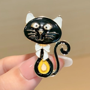 Vue macro détaillée d'une jolie broche chat en émail noir avec un détail de nœud doré