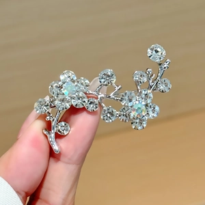 Macro shot of silver flower brooch with sparkling rhinestones held by hand details