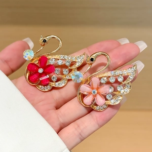 Elegante par de broches de cisne dorados con cristales brillantes y flores de esmalte