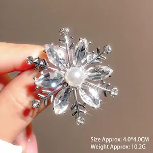 Close-up of silver snowflake brooch with sparkling crystals and a central pearl detail