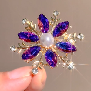 Macro shot of snowflake brooch with purple marquise gems, pearl and sparkling crystals