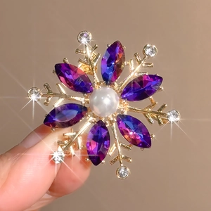 Golden snowflake brooch featuring a pearl center and sparkling purple marquis crystals