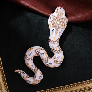 Detail of vintage snake brooch with white enamel, AB crystals, and gold-tone star engraving