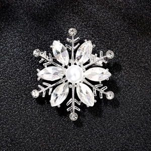Detailed view of silver snowflake brooch featuring clear zircons and central white pearl