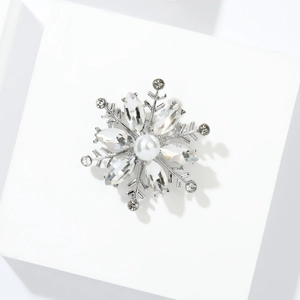 Close-up of snowflake brooch with silver alloy, crystal petals, and a central white pearl