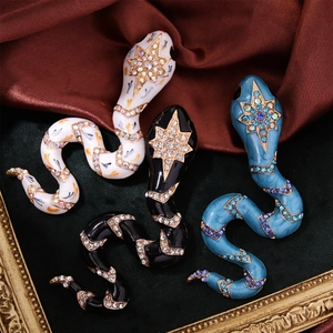 Macro detail of enamel snake brooches with rhinestones and star patterns on luxury velvet