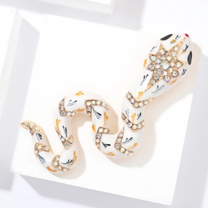 Macro shot of white enamel snake brooch with gold plating and colorful rhinestones