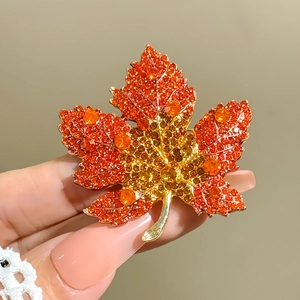 Close-up of maple leaf brooch with orange rhinestones on a gold-tone alloy base