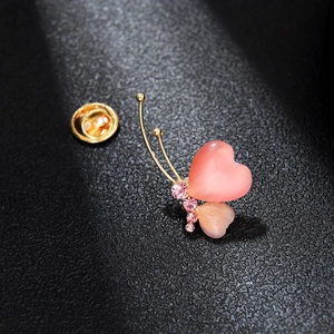 Macro detail of butterfly brooch with heart-shaped gemstones and pink rhinestones