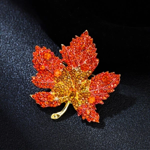 Macro detail of luxury maple leaf brooch with gradient crystals and gold metal finish