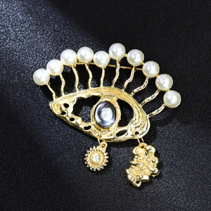 Detailed close-up of eye-shaped brooch with pearls and sun charm on black leather