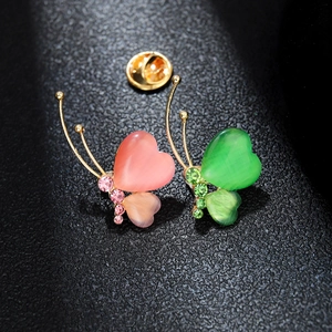 Elegant gold butterfly brooch with pink and green cat-eye stones on dark leather