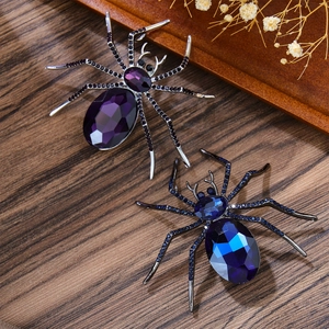 Spilla vintage a ragno con cristalli viola e blu su sfondo di legno scuro
