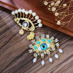 Baroque Evil Eye brooch set with pearls and tassels on a vintage aesthetic background