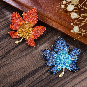 Detail of maple leaf brooches with vibrant rhinestones on a dark textured background