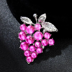 Macro shot of silver grape brooch with pink pearls and detailed leaf textures