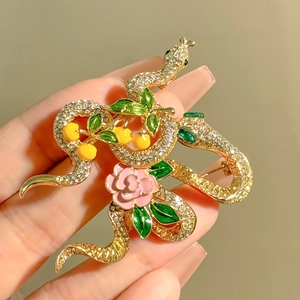 Elegant gold snake brooch with crystal rhinestones, pink rose, and green enamel leaves