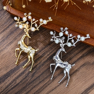 Broches élan élégantes en or et argent avec perles et cristaux sur fond de bois