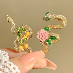 Detail of crystal-encrusted snake brooches with enamel flowers and golden finish