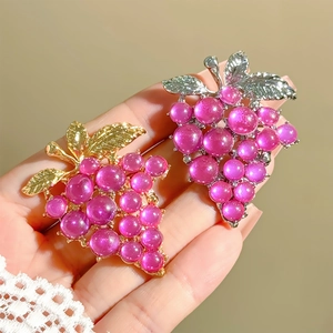 Close-up of elegant grape brooches with purple beads and textured metal leaves