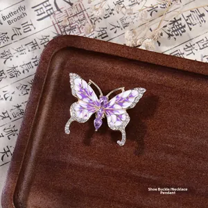 Détail d'une breloque papillon violette avec strass et émail sur un plateau en bois
