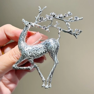 Vintage silver stag brooch with flowering antlers shown as a handheld accessory