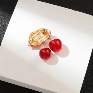 Creative cherry brooch with red lip element and resin beads on a white pedestal