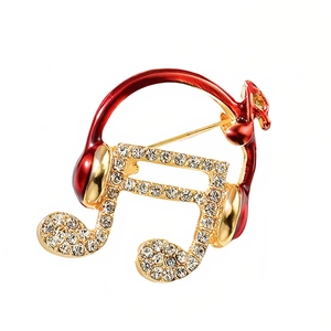 Exquisito broche dorado de nota musical y auriculares con esmalte rojo y circonitas