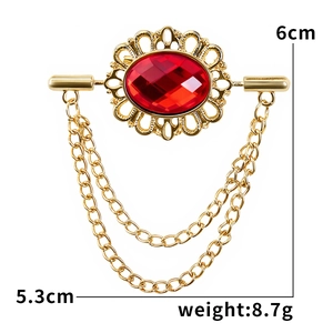 Macro shot of vintage red gemstone brooch with gold metal lace and twin tassel chains