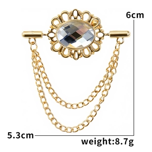 Macro shot of gold vintage brooch with oval crystal gem and elegant metal tassels