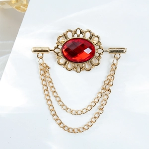 Vintage gold brooch with red oval gemstone and elegant tassel chains on white fabric