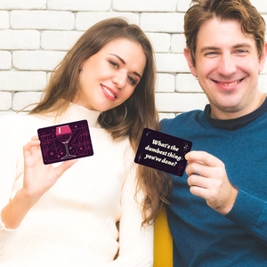 Close-up of adults playing a social drinking card game with purple and pink question cards