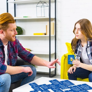 Group of friends playing drinking game cards with blue design and white text in living room