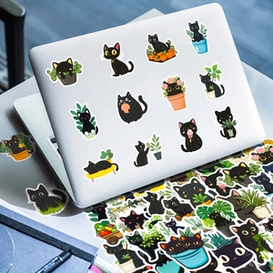 Close-up of waterproof black cat doodle stickers applied on a silver laptop surface