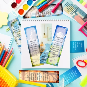 Artistic paper bookmarks with landscapes and quotes on a notebook with stationery items