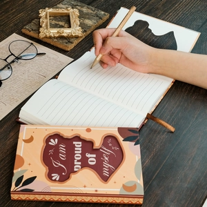 Carnet artistique avec citation I am proud of myself sur un bureau en bois