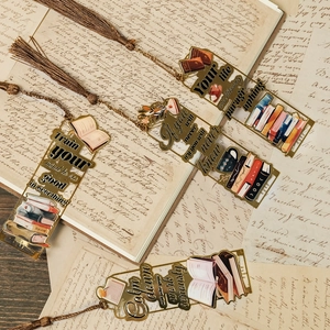 Detail von vier goldenen Metall-Lesezeichen mit bunten Illustrationen und Seidenquasten